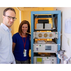 Lead researchers Drs. Martin Reinhardt and Susanne Votruba stand next to the carbon dioxide and oxygen analyzers, and outside the whole-room indirect calorimeter.