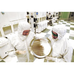 Dr. Michael Liehr (left) of SUNY Polytechnic Institute’s Colleges of Nanoscale Science and Engineering and Bala Haran (right) of IBM Research inspect a wafer comprised of 7nm (nanometer) node test chips in a clean room. (Credit: Darryl Bautista)