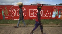 MONROVIA, LIBERIA: People pass an Ebola awareness mural on October 2, 2014 in Monrovia, Liberia. More than 3,200 people have died in West Africa due to the epidemic.