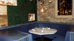 Booth inside Savoie Restaurant with artificial boxwood hedge on wall.