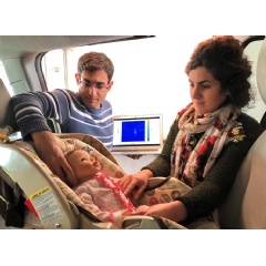 Graduate students Mostafa Alizadeh, left, and Hajar Abedi position a doll, modified to simulate breathing, in a minivan during testing of a new sensor.