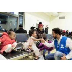 Dawit America Girmay, a UNHCR cultural mediator, entertains an Eritrean child after she arrived in Rome, Italy, on a relocation flight from Niger.  © UNHCR/Alessandro Penso