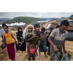 A Rohingya boy carries an older relative up a muddy path at the Kutupalong extension site, built on land allocated by the Bangladesh Government. © UNHCR/Paula Bronstein