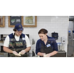 Two associates working on a pizza in deli