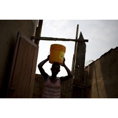 Gloria*, 13 carries water at her home in Musaga, in Bujumbura, Burundi in 2016